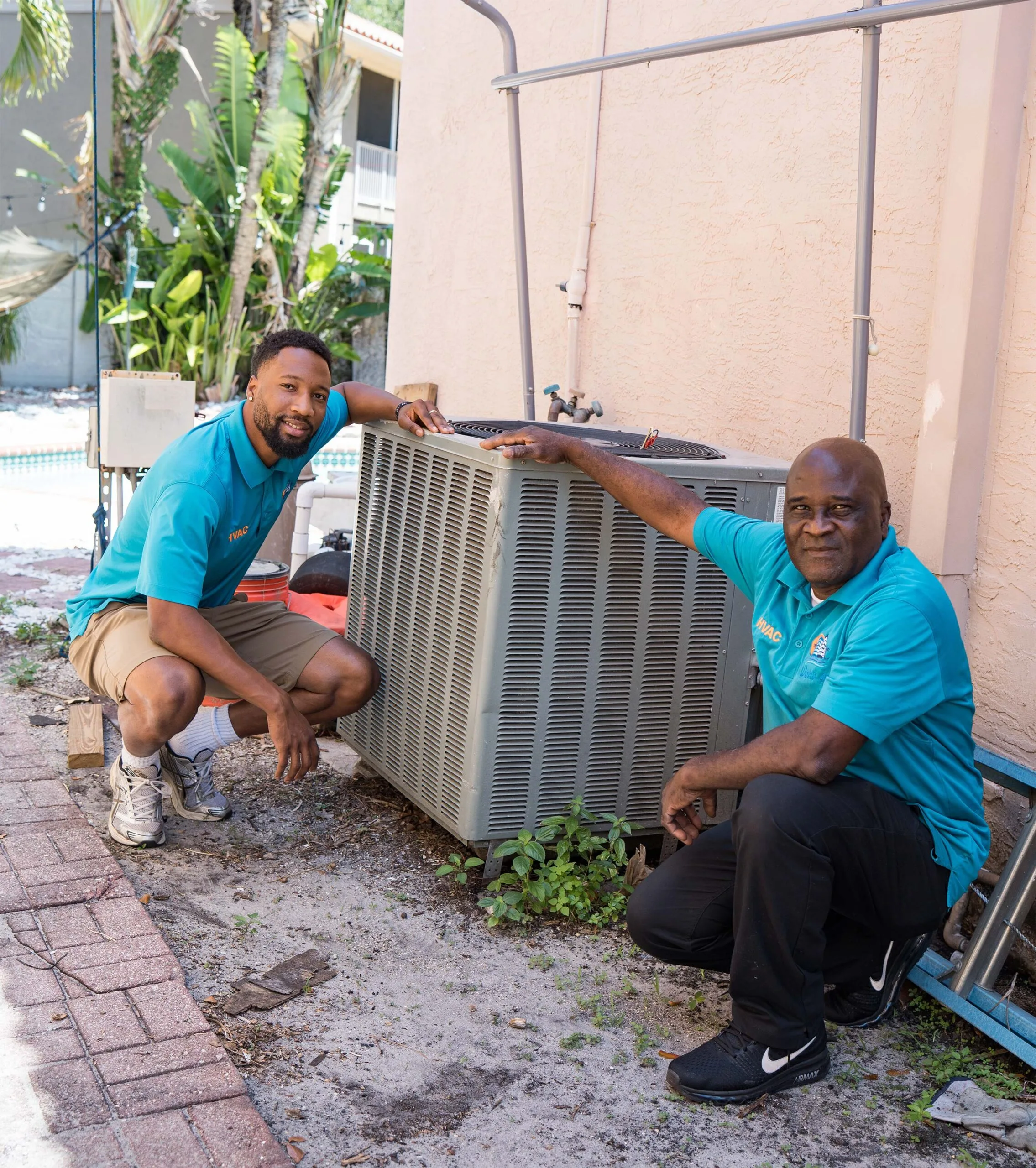 World Air HVAC technicians next to an AC unit in South Florida