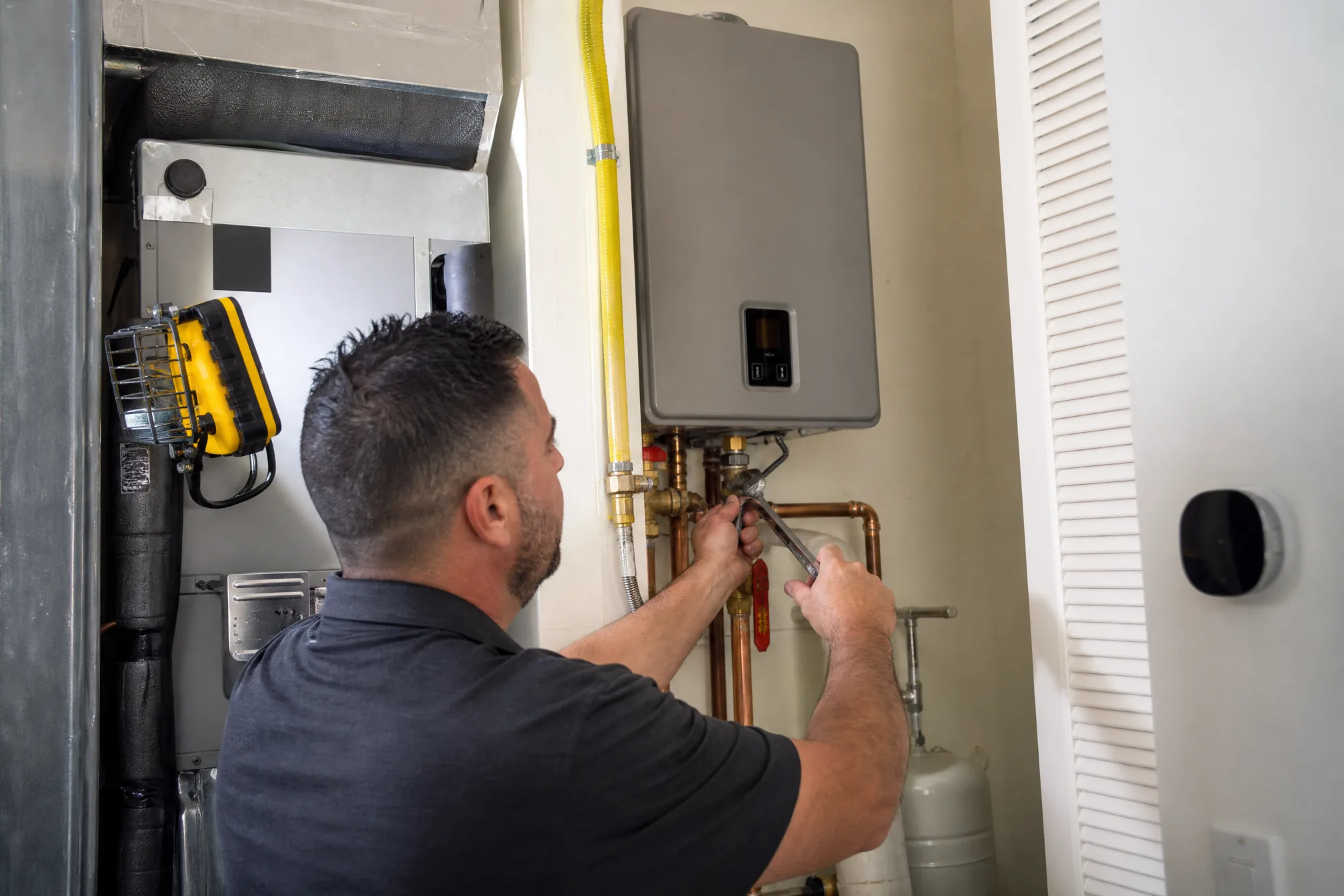 HVAC technician installing a compact tankless water heater on a wall in a Florida utility closet